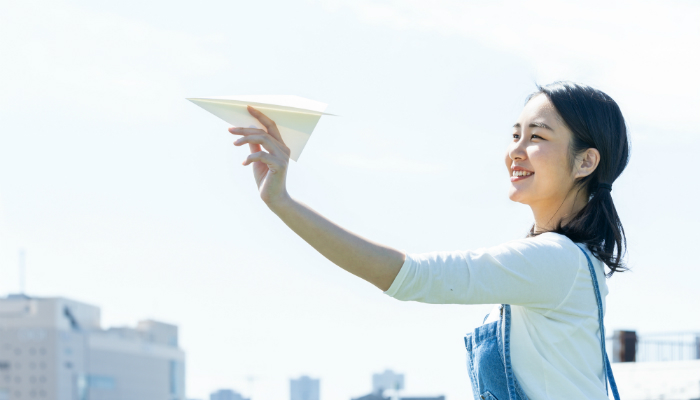 紙飛行機を飛ばす女性